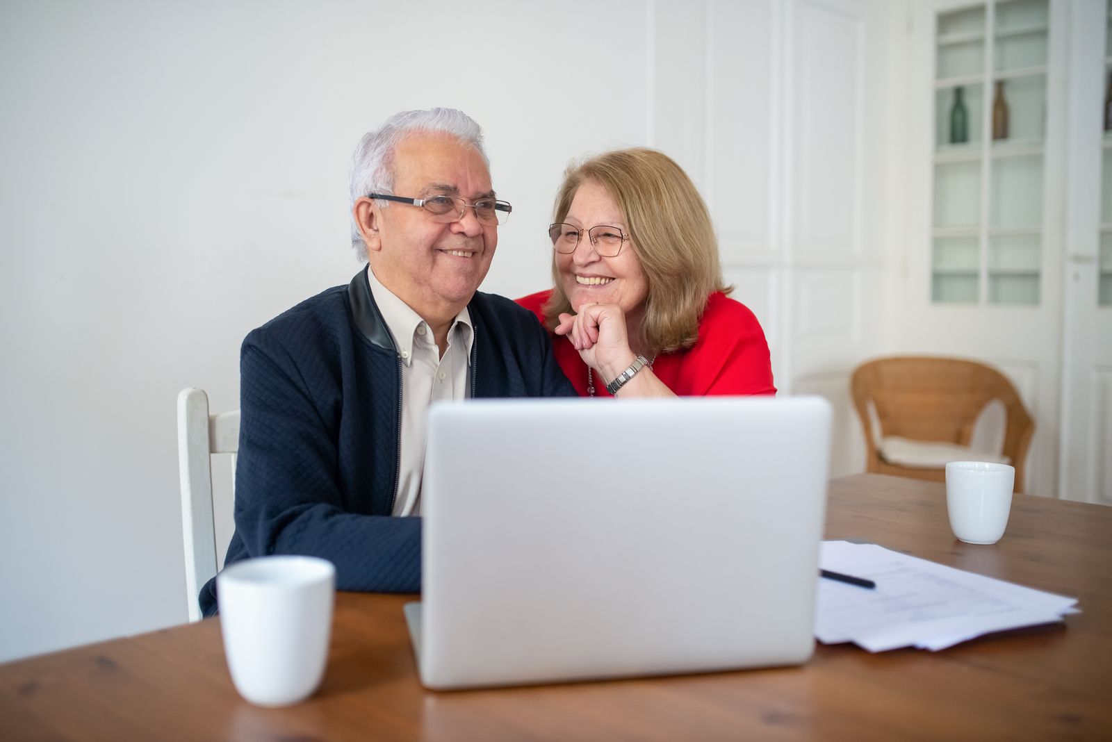 Couple souriant qui consulte ses comptes sur un ordinateur portable