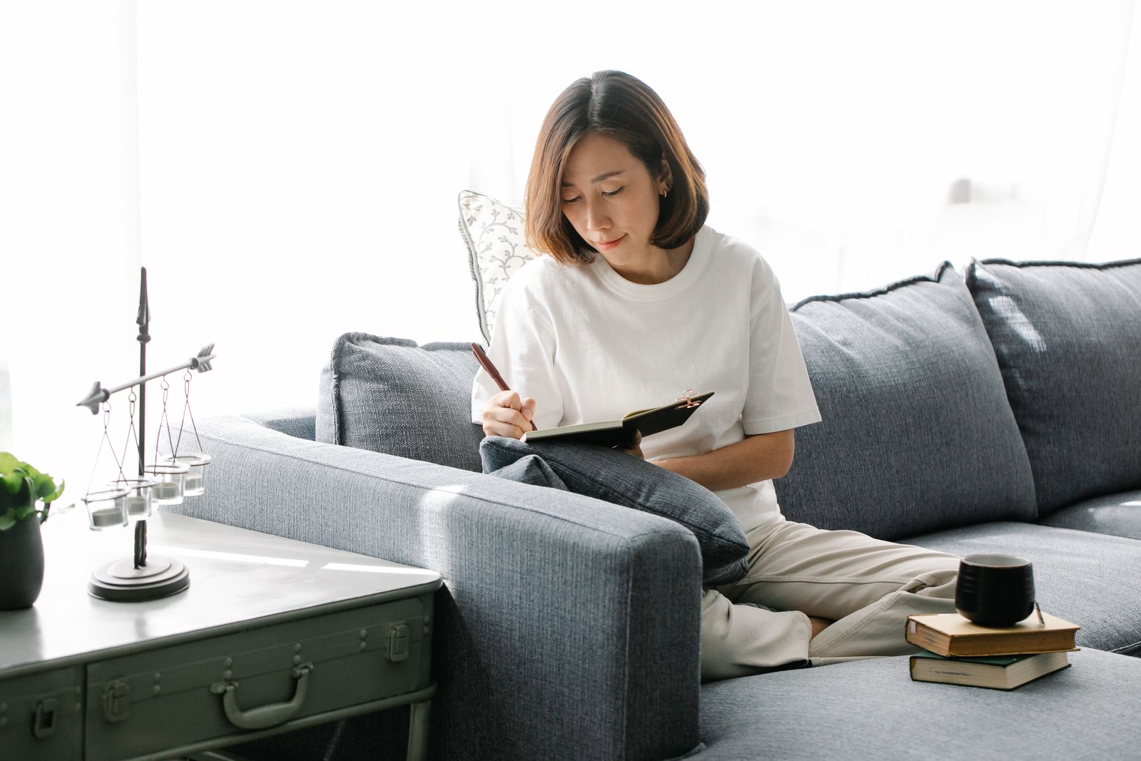 Femme qui note ses projets dans un carnet, dans son salon